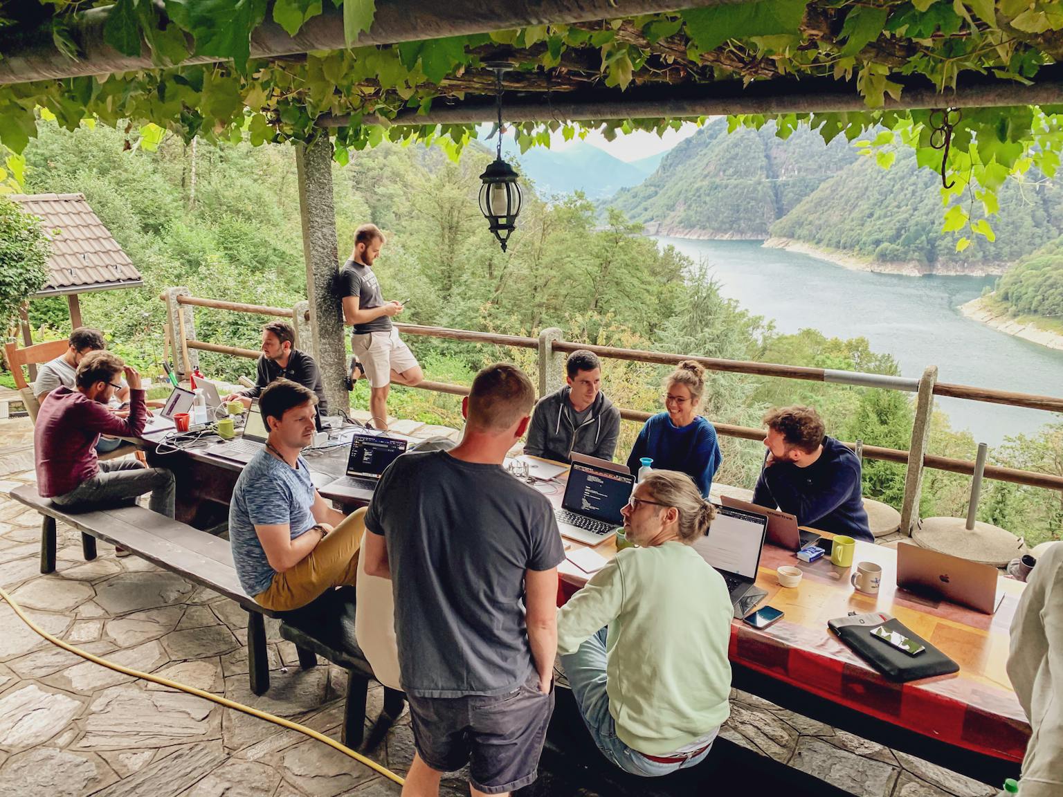 smartive Team am arbeiten an einem Tisch im freien mit dem Valle Verzasca im Hintergrund